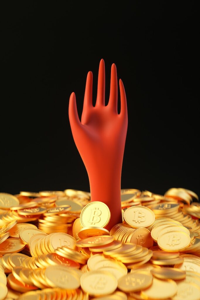 a pile of gold coins with a red hand sticking out of it